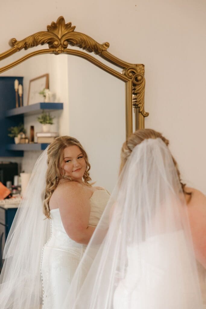 A bride takes one last look at herself after her veil is put in her hair.